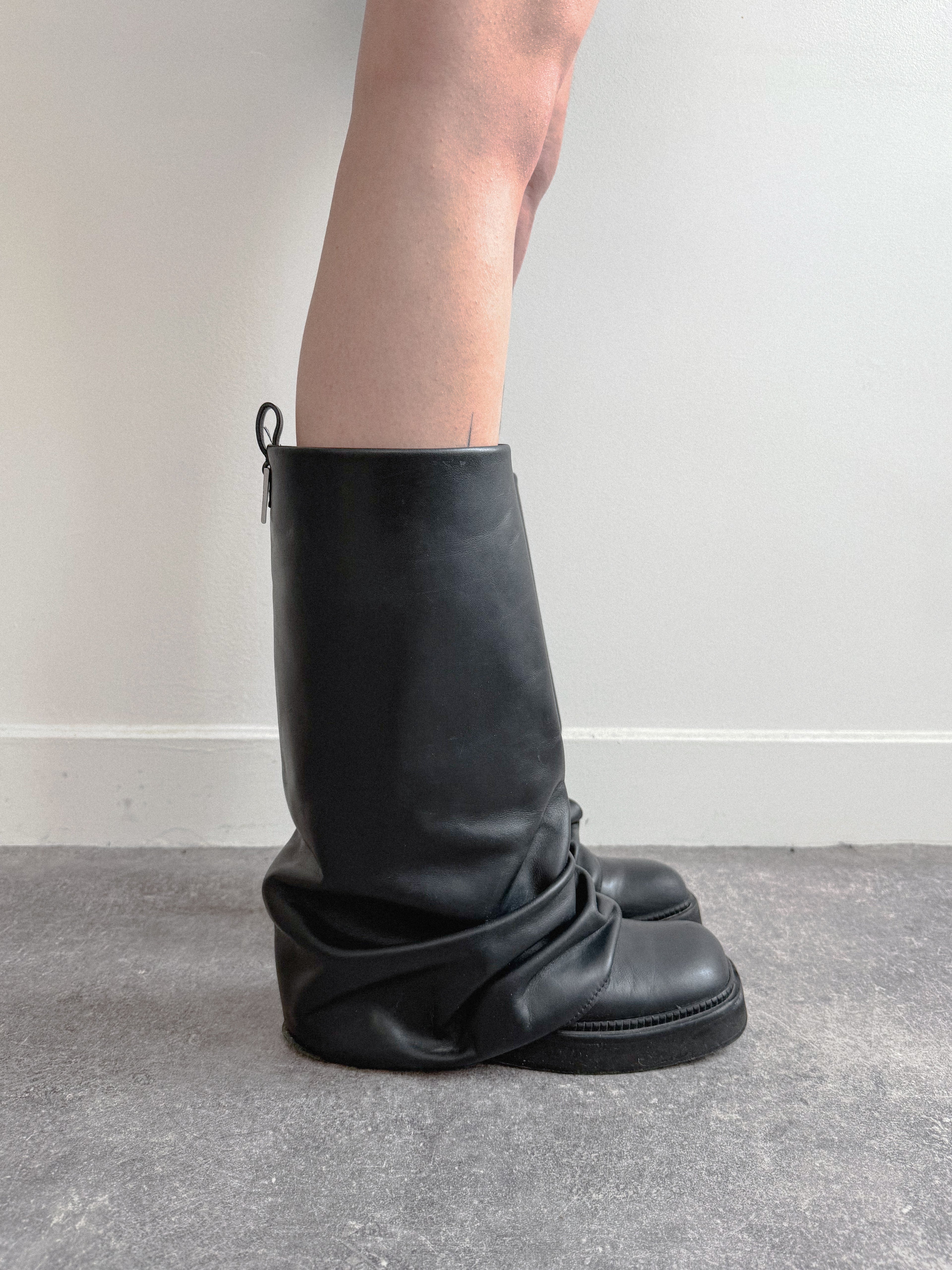 Black leather boot on a plain background