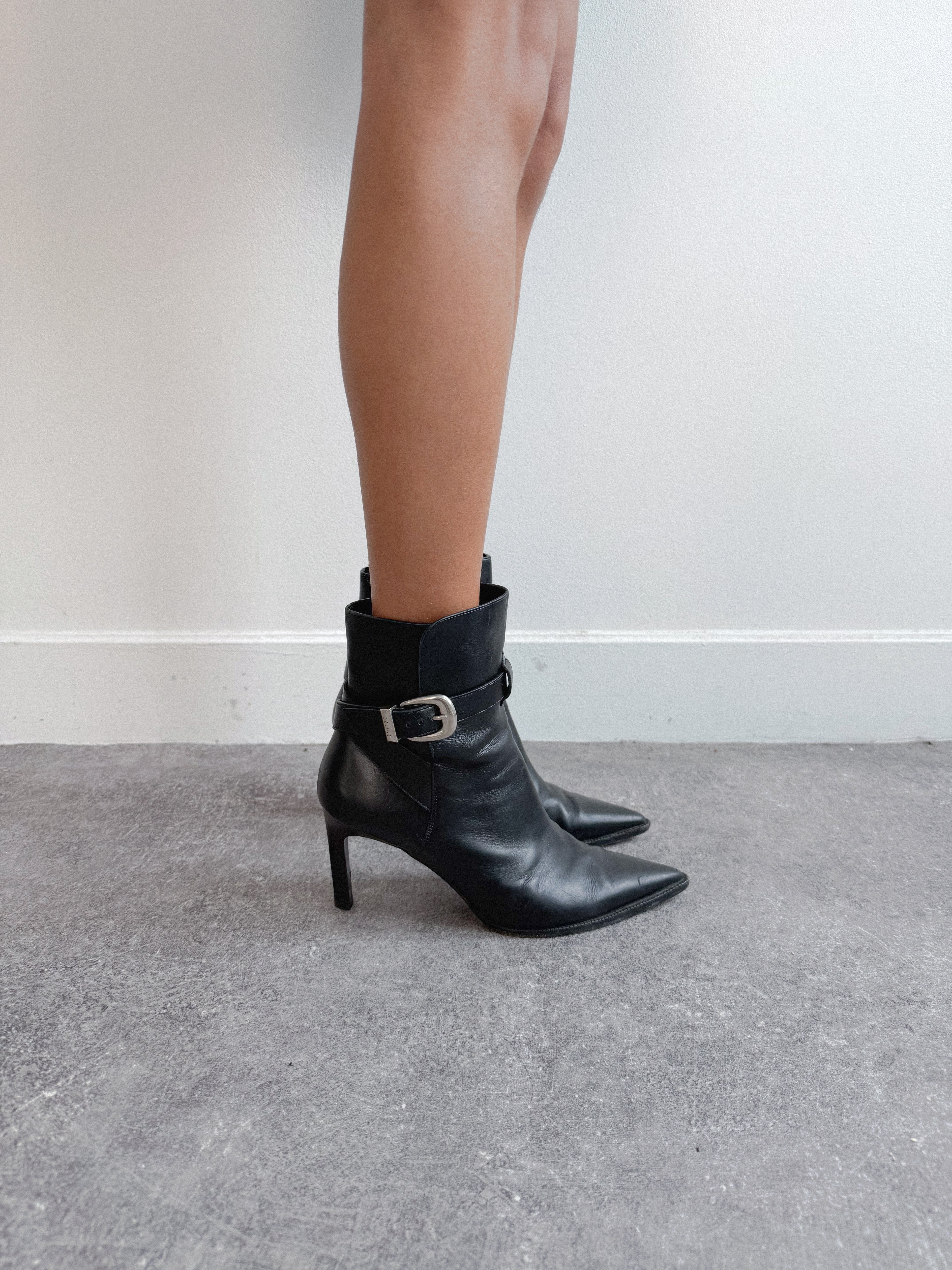 Black ankle boots with a buckle on a neutral background