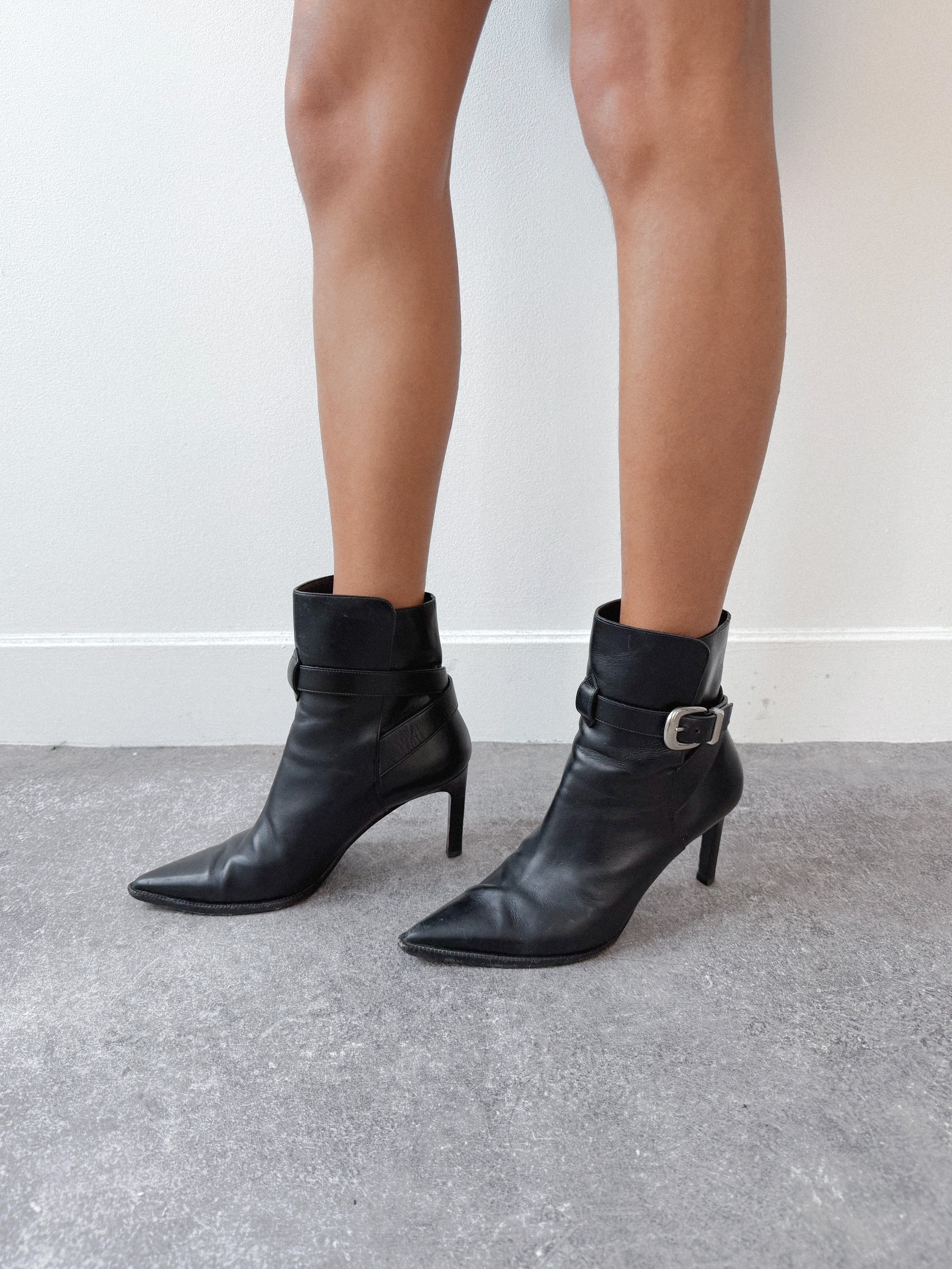 Black ankle boots worn by a person on a neutral background