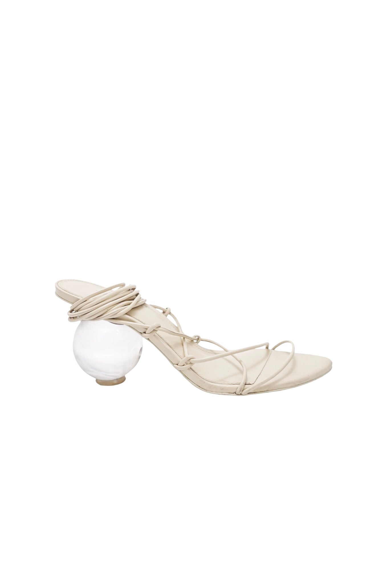Beige high-heeled shoe with a clear glass sphere on a white background