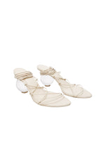 Pair of beige strappy sandals with white spherical elements on a white background