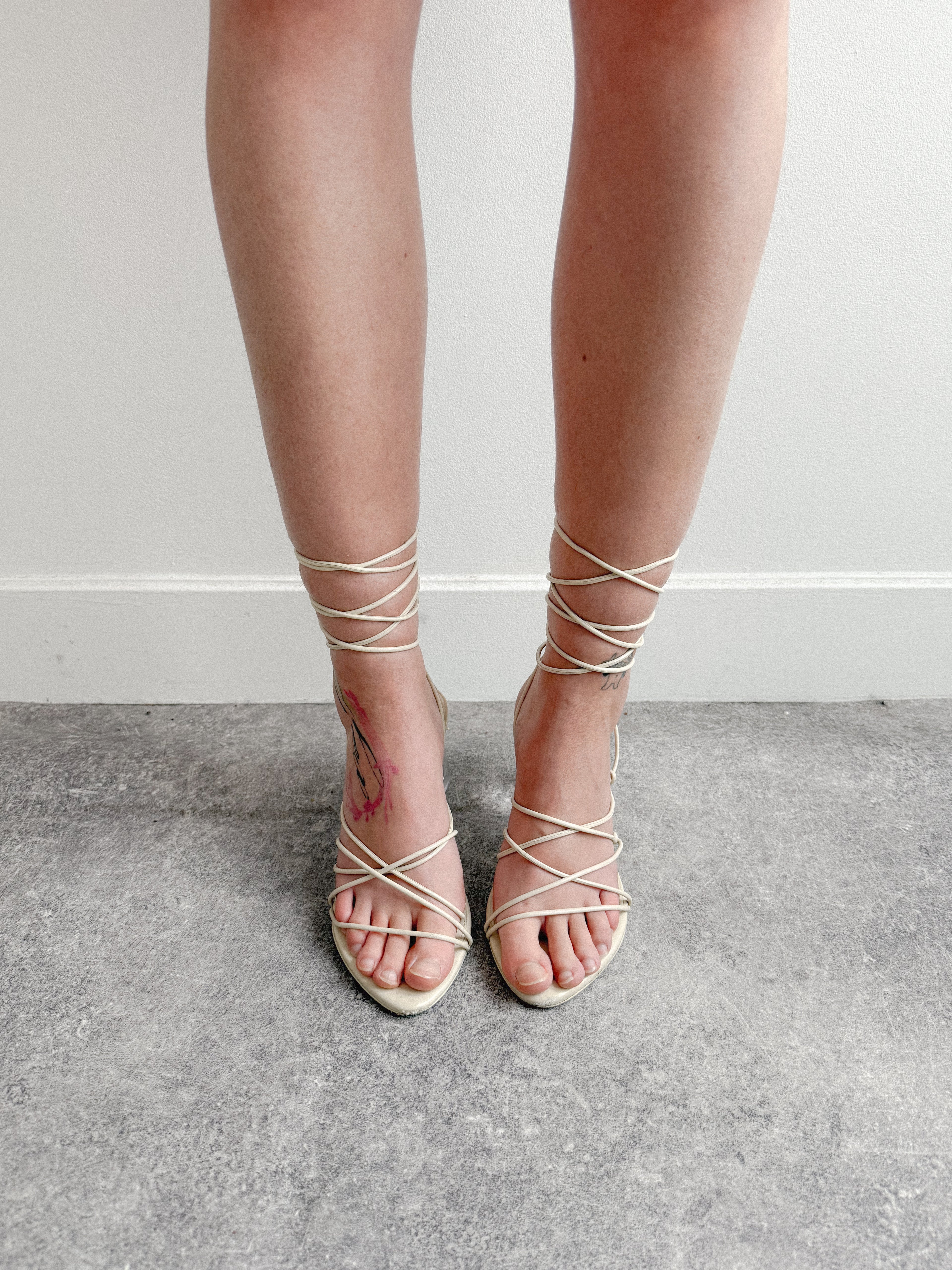 Strappy sandals worn with a neutral background