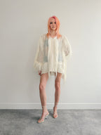 Person wearing a sheer white outfit with a plain background