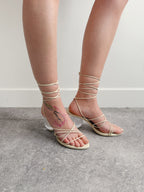 Strappy sandals worn with minimal clothing on a neutral background