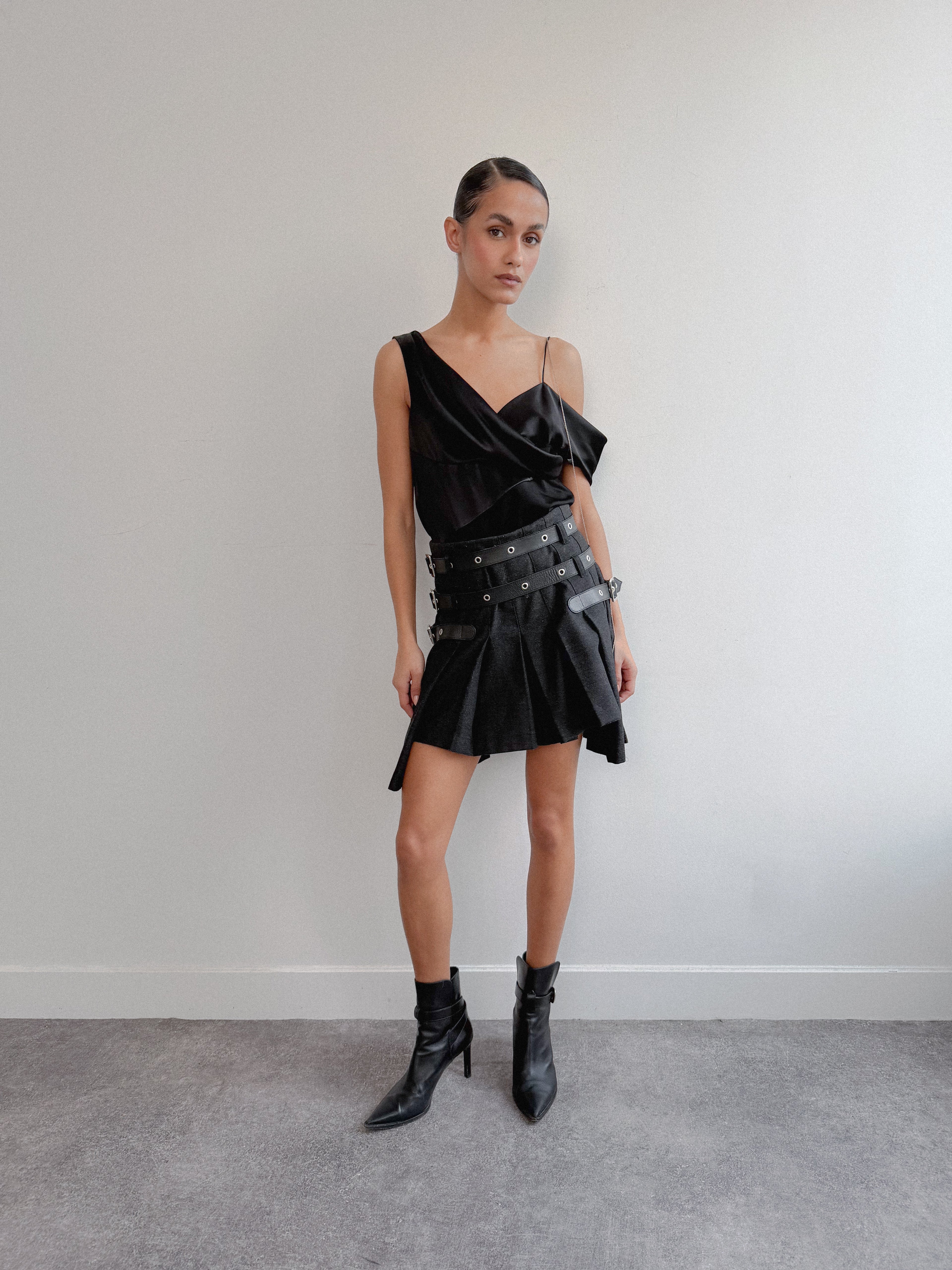 Woman wearing a black dress with leather accents against a plain background