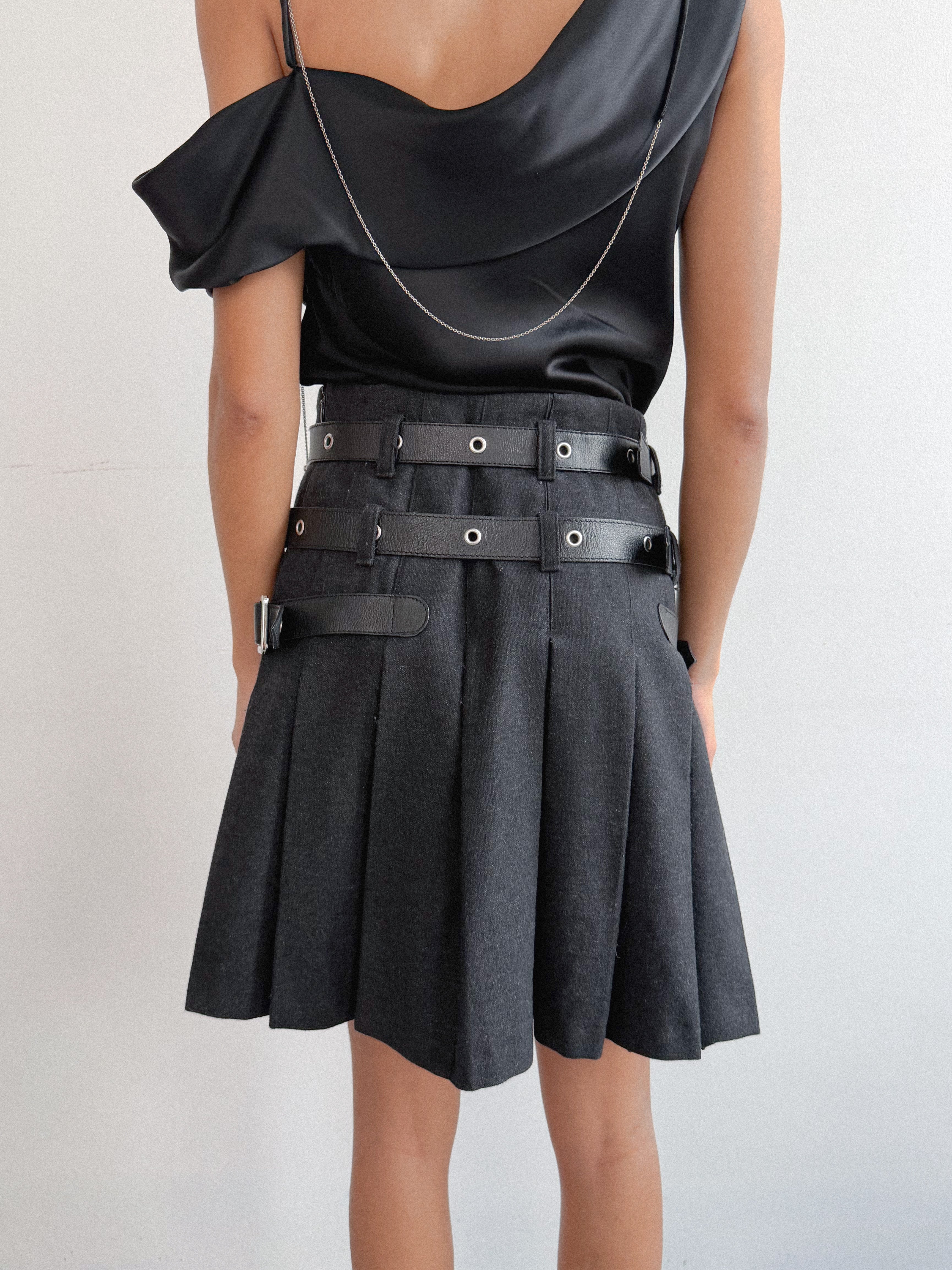 Person wearing a black outfit with a belt on a white background