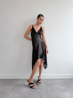 Woman wearing a black slip dress against a plain background