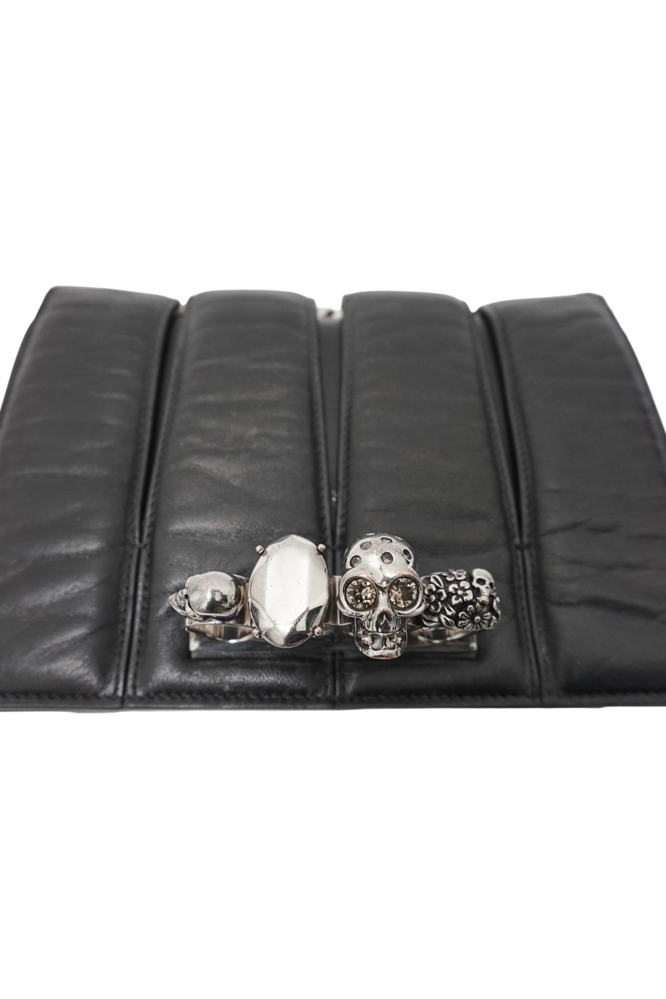 Black leather clutch with skull and gemstone design on a white background