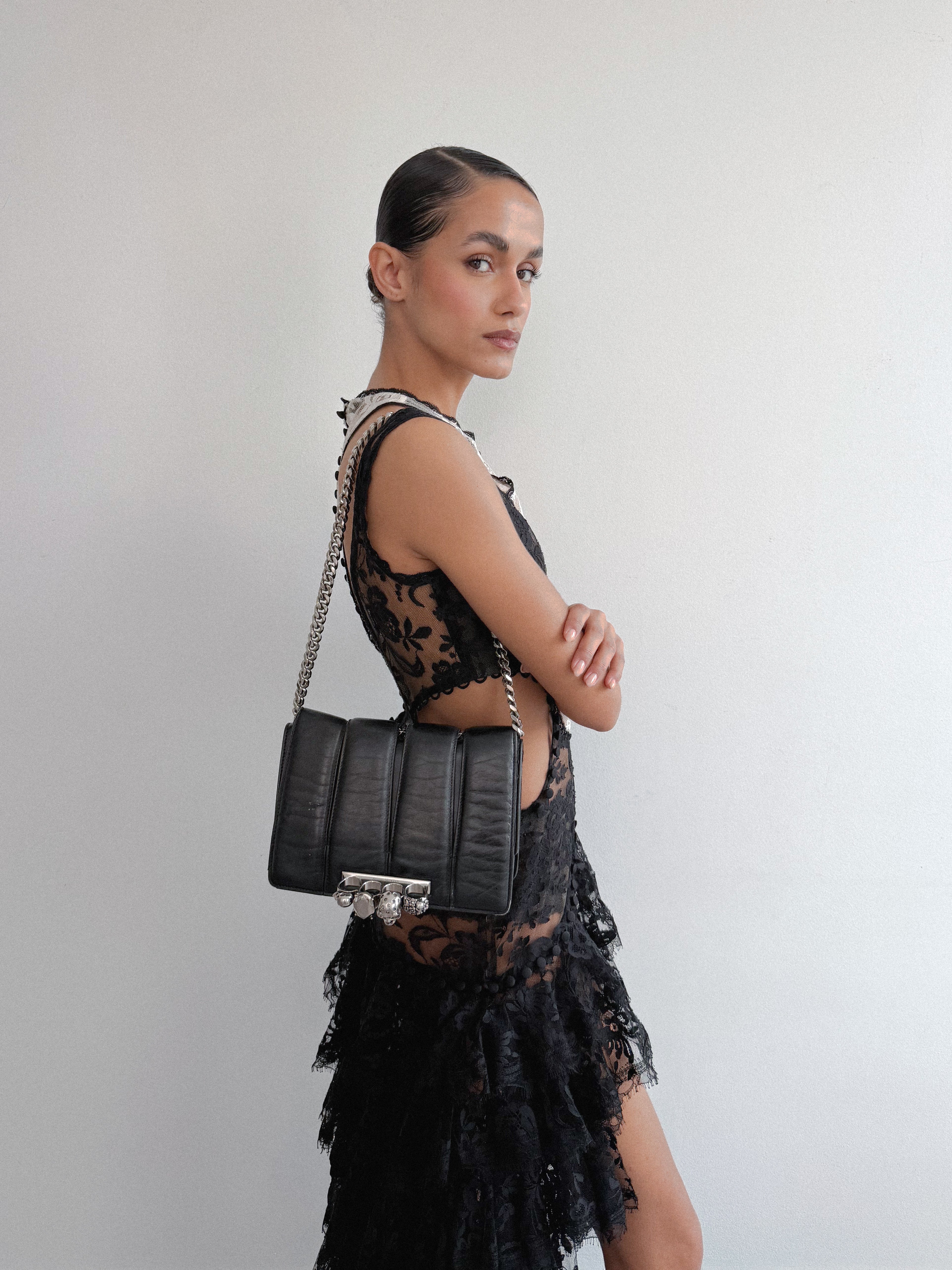 Woman holding a black handbag against a plain background