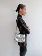 Woman holding a silver handbag against a plain background