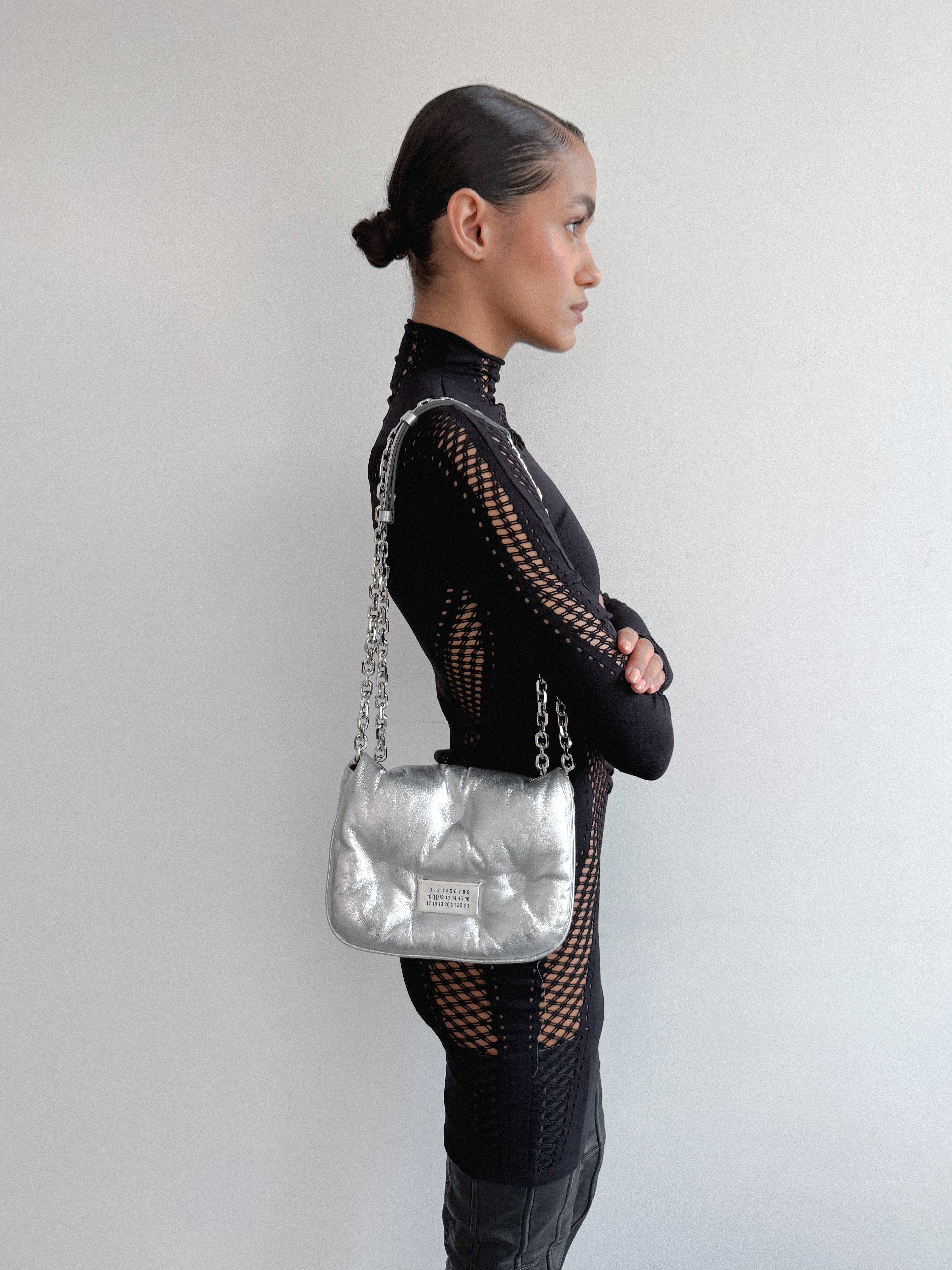 Woman holding a silver handbag against a plain background