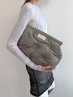 Person holding a gray baby carrier against a plain background