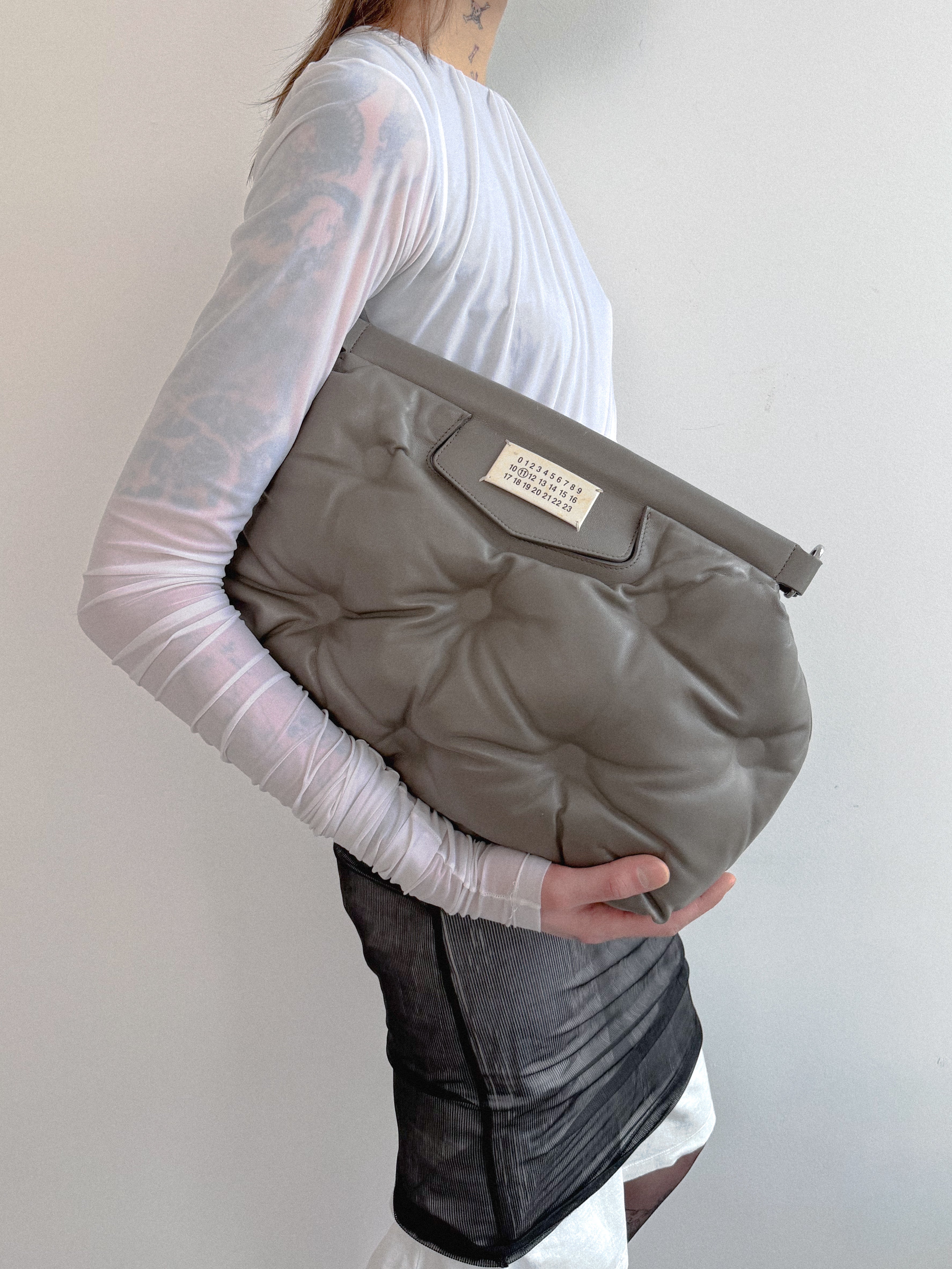 Person holding a gray baby carrier against a plain background