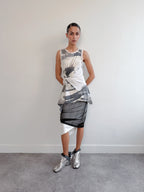 Woman wearing a sleeveless top and skirt with abstract patterns against a plain background