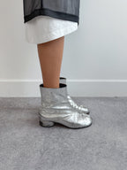 Person wearing silver metallic boots on a plain background