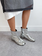 Person wearing silver metallic boots on a plain background