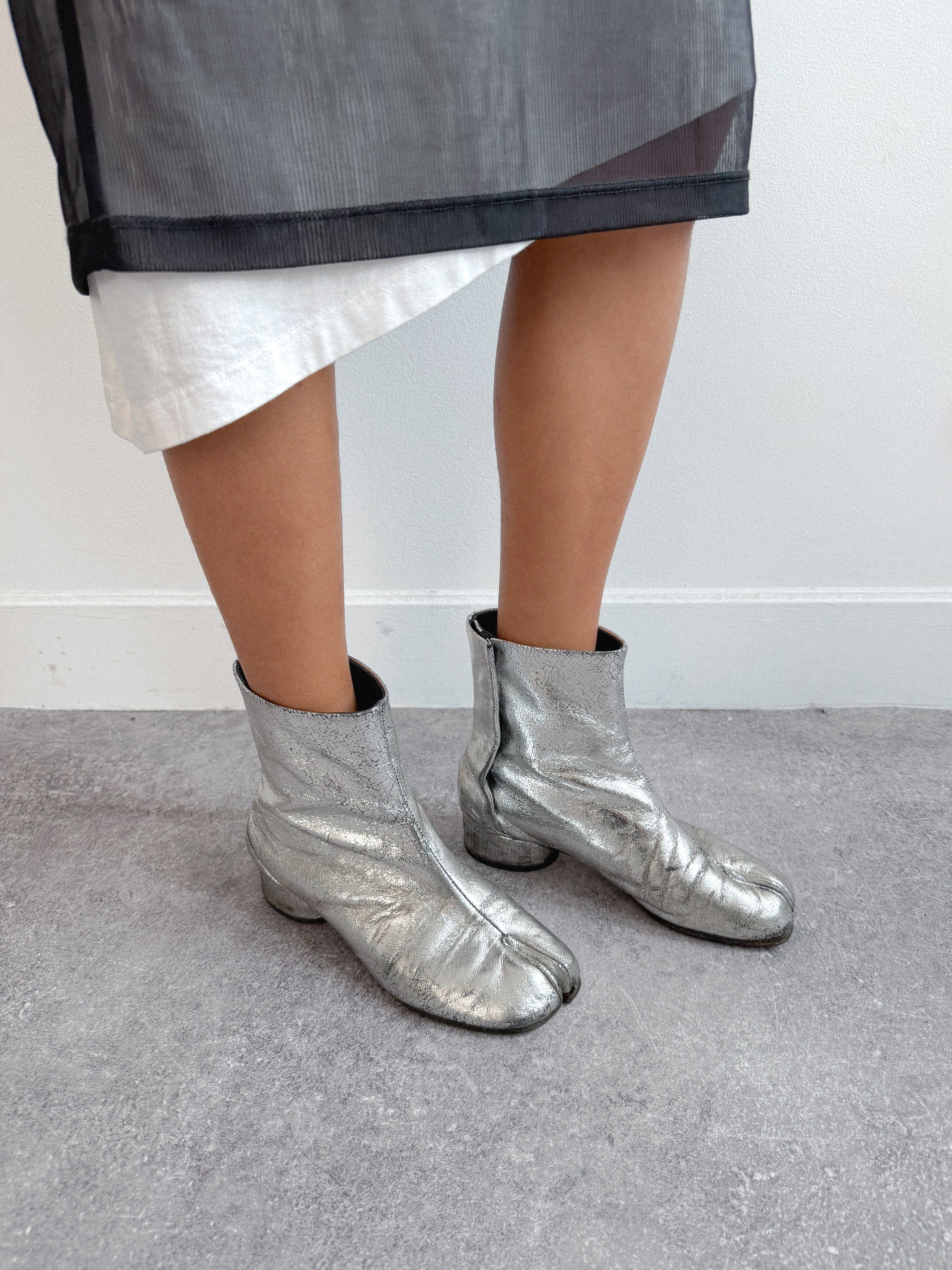 Person wearing silver metallic boots on a plain background