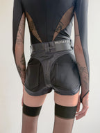 Person wearing a black outfit with 'Mugler' branding on a plain background