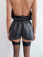 Person wearing black shorts and stockings on a plain background