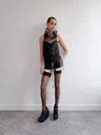 Person wearing a black outfit with sheer elements against a plain background