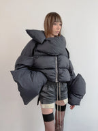 Person wearing a large dark gray puffer jacket against a plain background
