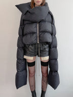Person wearing a large black puffer coat with a minimal background