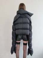 Person wearing a large black puffer jacket with a plain background