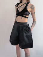 Person wearing a black outfit with a top and shorts on a plain background