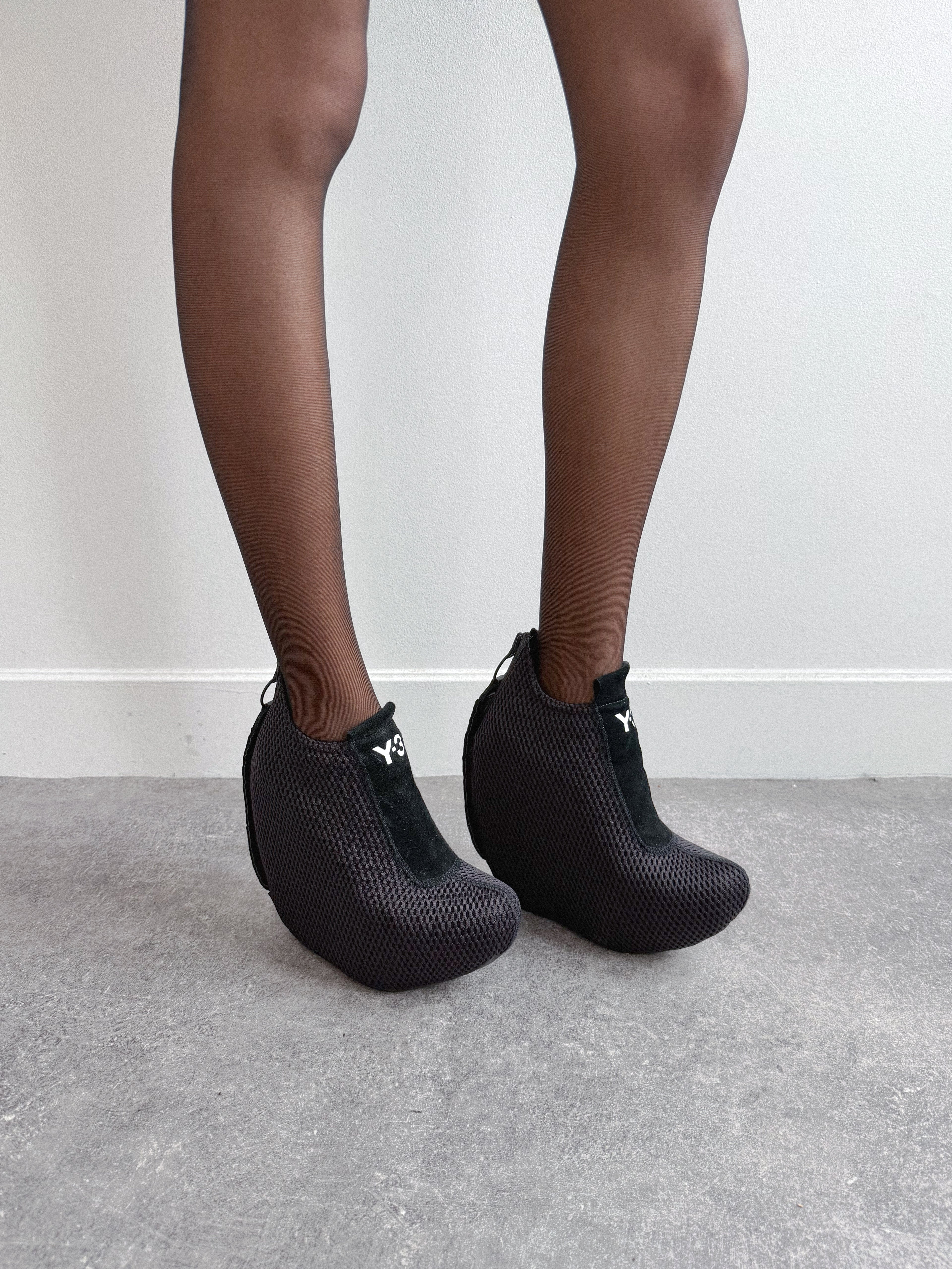 Black textured ankle boots worn with tights on a neutral background