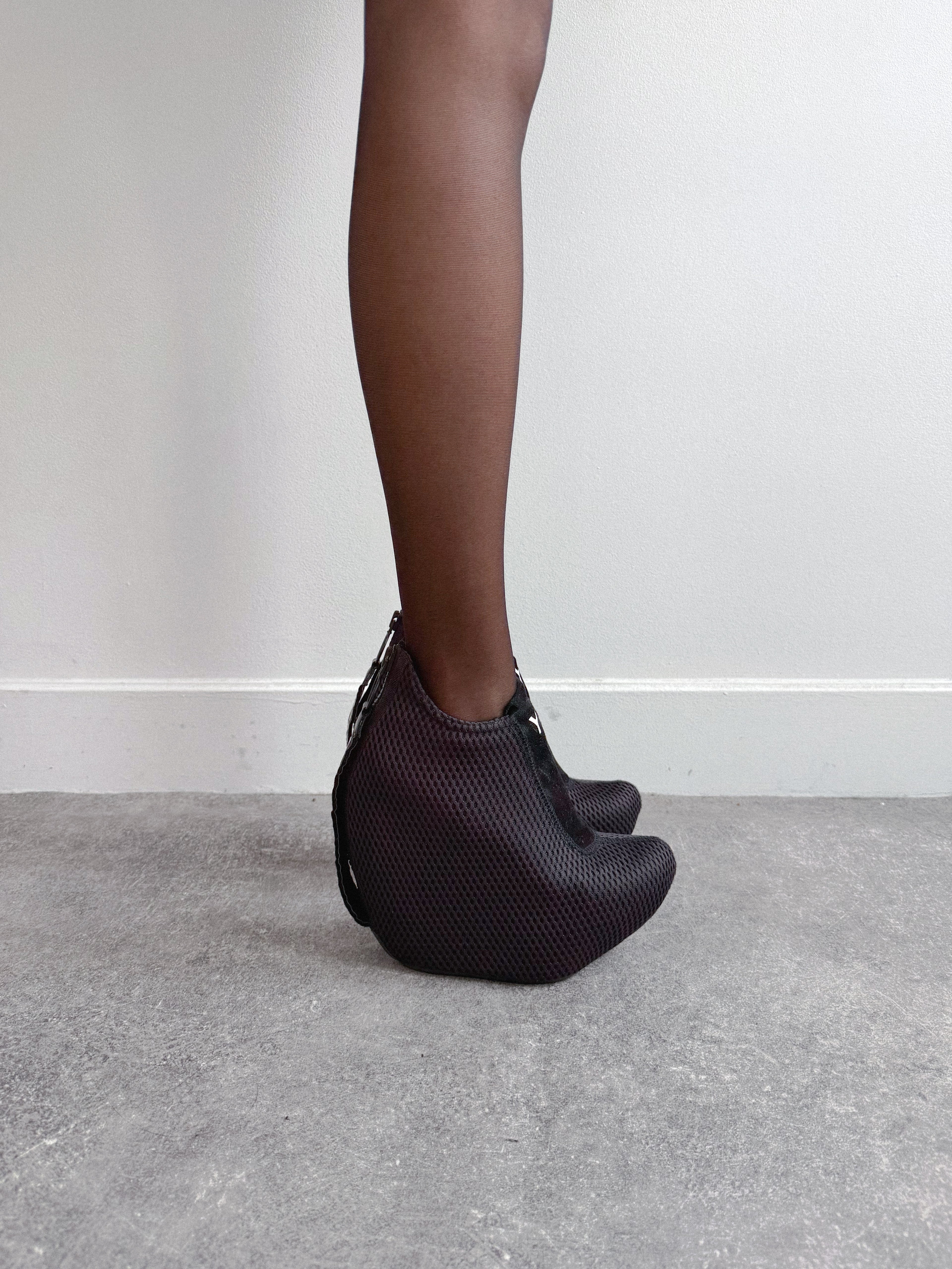 Person wearing black mesh shoes on a plain background