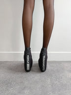 Black shoes with visible branding on a neutral background