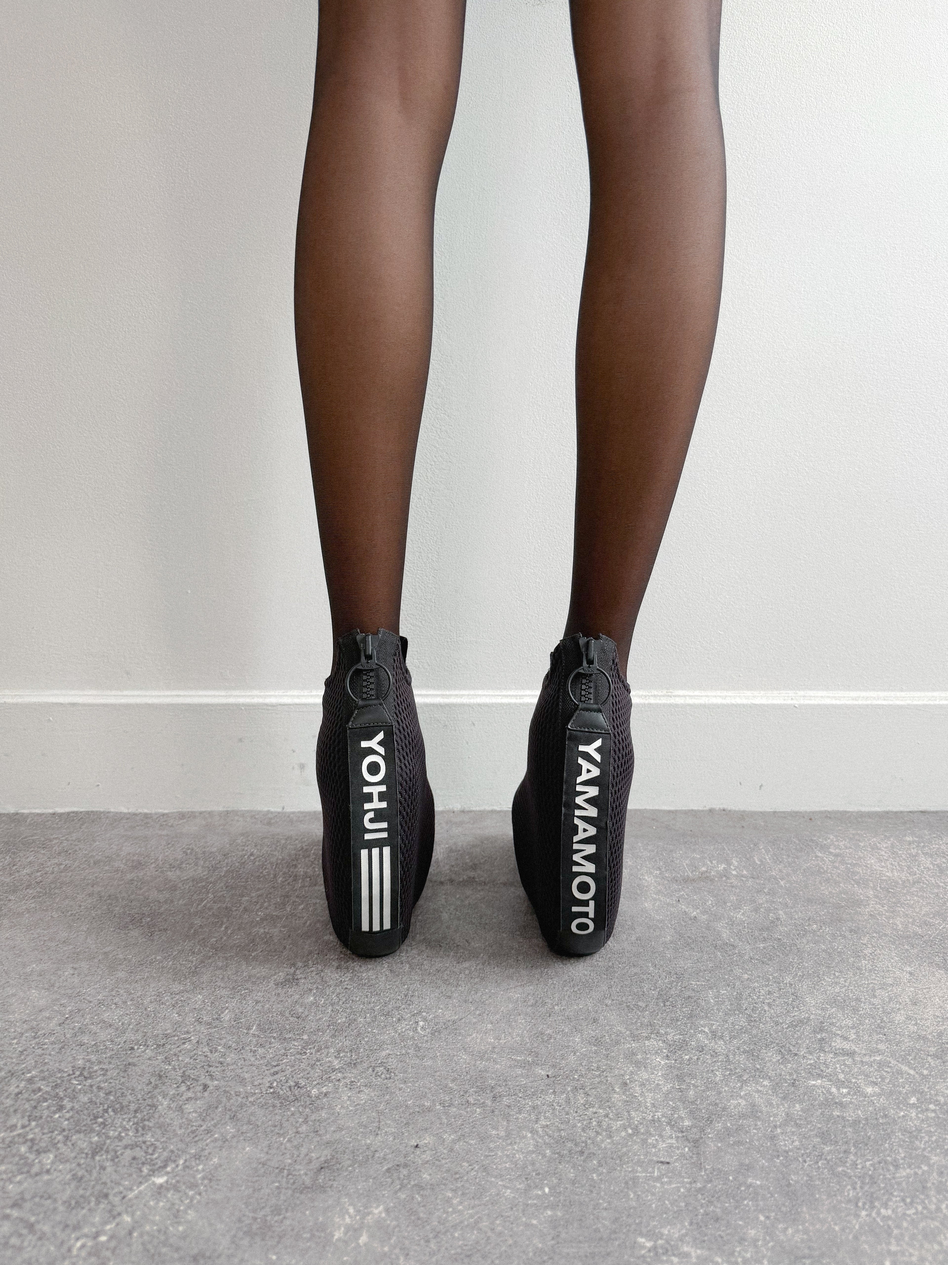 Black shoes with visible branding on a neutral background